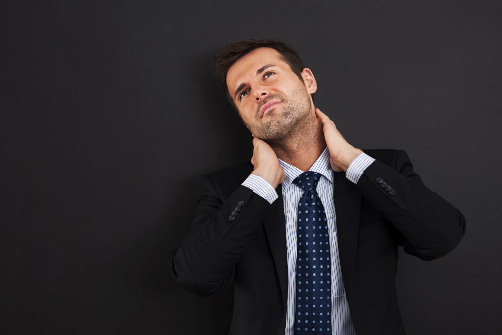 Person experiencing neck pain on one side while holding the painful area of the neck.