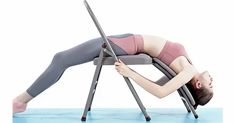 Woman using an inversion table exercise machine for lower back pain relief and spinal stretching.