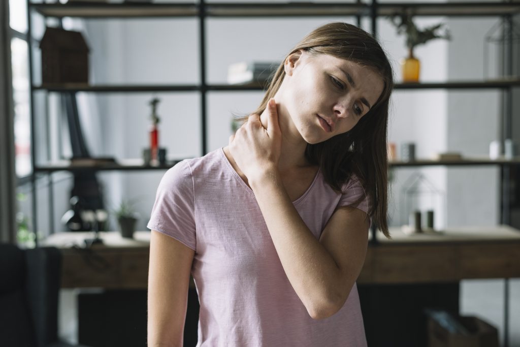 Person holding their neck due to headache caused by neck pain
