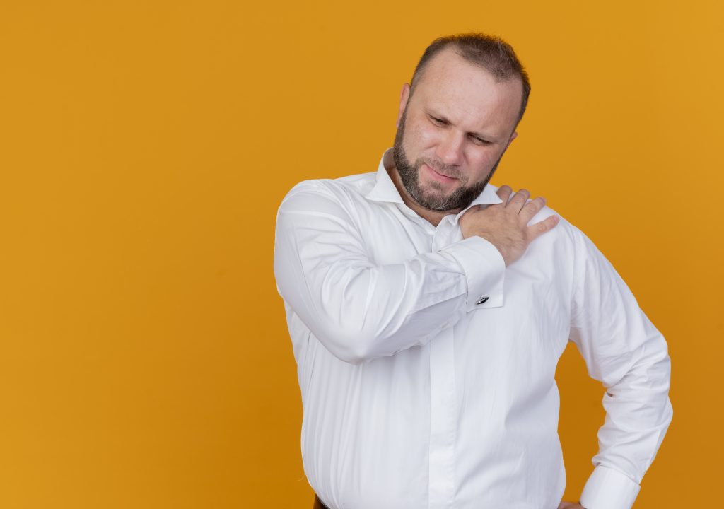 Person holding the front of their shoulder while lifting their arm due to shoulder pain caused by rotator cuff injury, shoulder impingement, or biceps tendinitis.