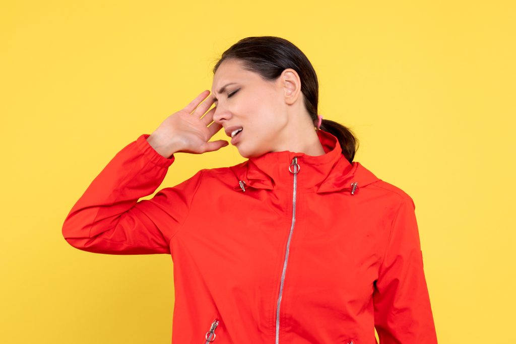 Person holding the bridge of the nose due to pain accompanied by a headache and facial pressure.