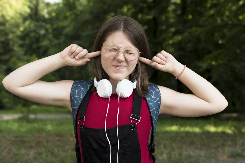 Person covering their ears due to sensitivity to everyday sounds, illustrating hyperacusis and sound sensitivity.