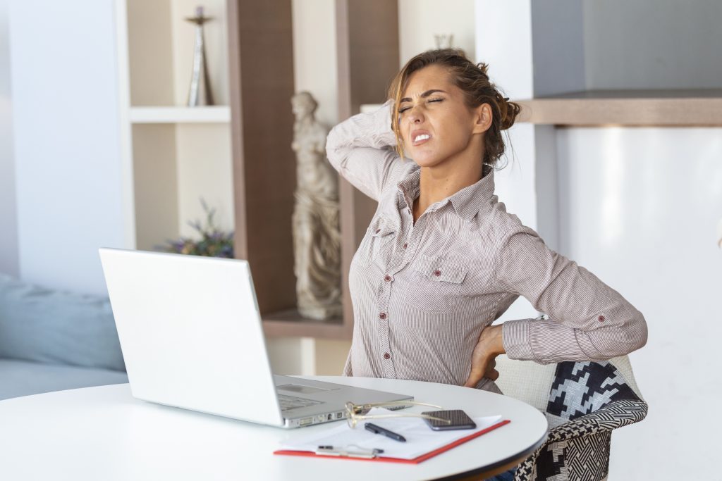 Back Pain After Sitting Too Long affecting an office worker with lower back pain while sitting at a desk