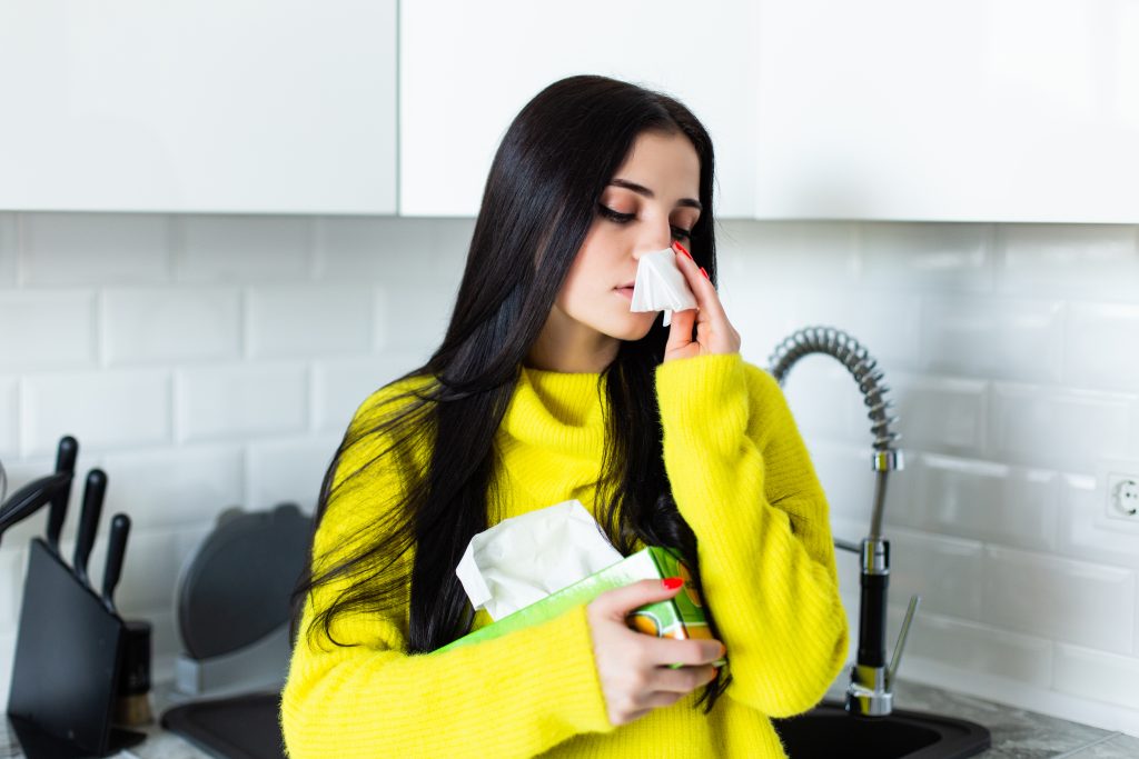Person experiencing mild sinus discomfort while touching the forehead, illustrating a silent sinus infection with few or no noticeable symptoms.